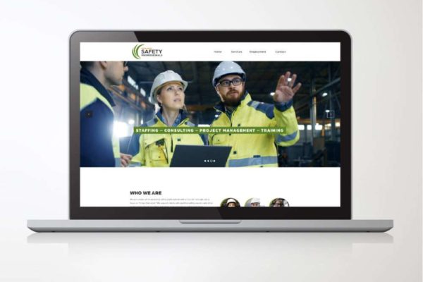 A laptop screen displaying the website of Safety Professionals, featuring professionals in safety gear collaborating in an industrial setting.